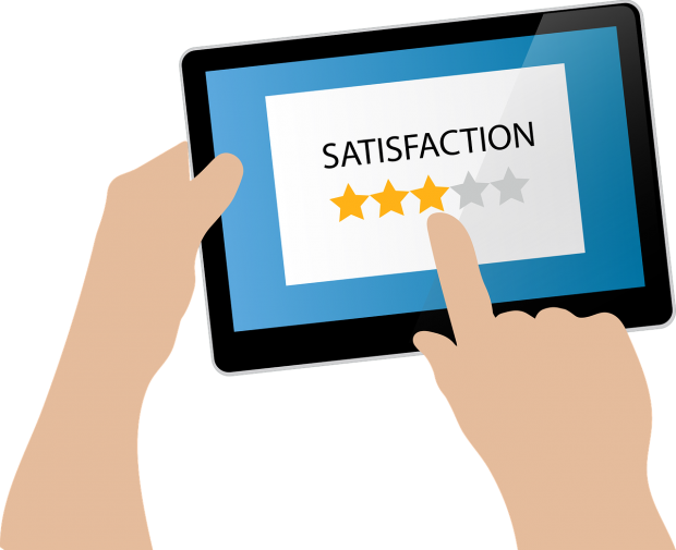 Hand holding a tablet. The tablet displays the word satisfaction with 5 stars underneath it